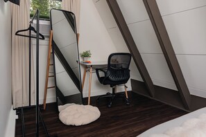 Ein kleines, kompaktes Zimmer mit Schreibtisch, Stuhl und einem kleinen Topfpflanzen.