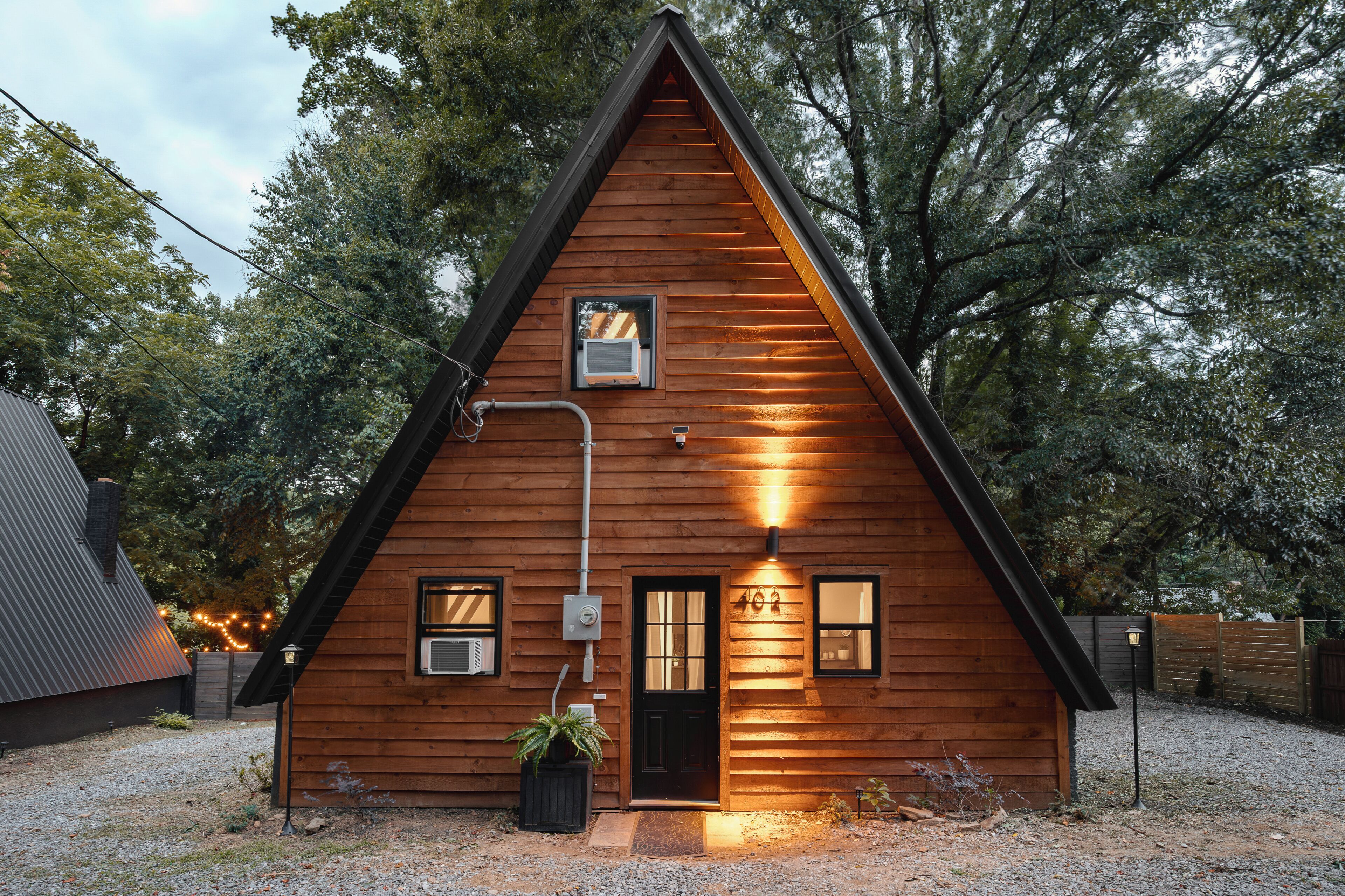 A wooden cabin with a triangular roof, a front door, and two windows.