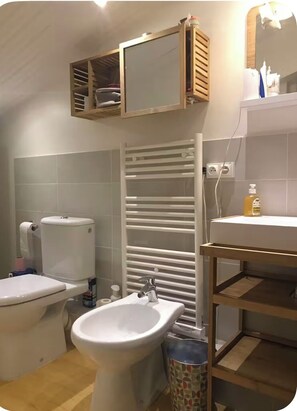 Une salle de bain comprenant des toilettes, un bidet, un lavabo, un miroir et un porte-serviettes.