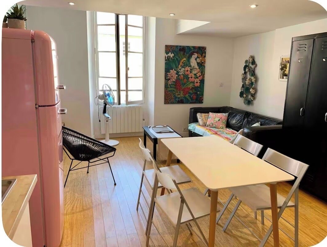 A modern kitchen with a dining area, a refrigerator, a chair, a table, and a sofa.