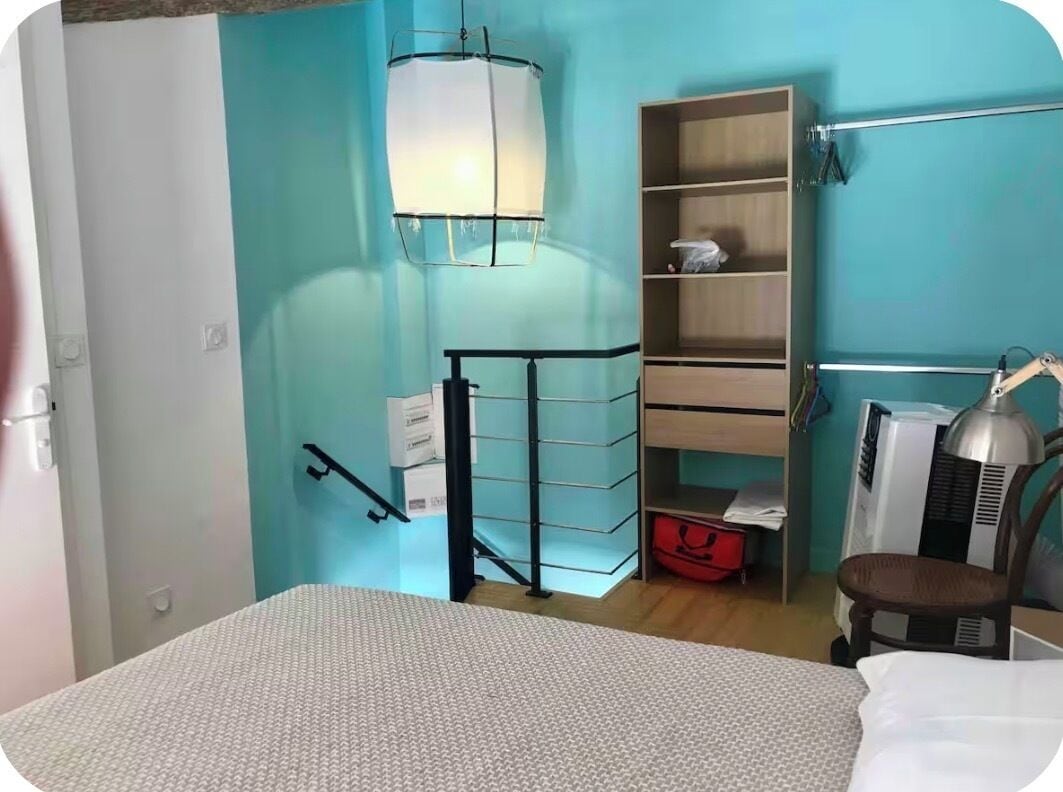 Ein Schlafzimmer mit einem Bett, einem Nachttisch, einer Lampe, einem Regal mit Aufbewahrungsboxen und einem Kleiderschrank.