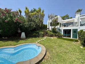 A modern house with a swimming pool, surrounded by lush greenery and palm trees. - Vilamoura Browns Villa by Homing (Loulé)