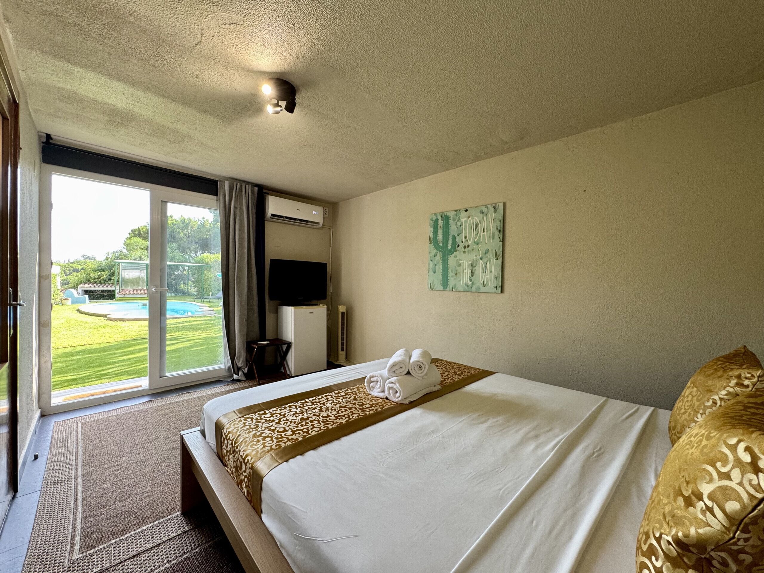 Une chambre d’hôtel équipée d’un lit, d’une télévision, d’un climatiseur, d’une décoration murale sur le thème des cactus et offrant une vue sur une piscine.