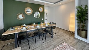 Zona pranzo con un tavolo lungo, sedie e una parete verde con specchi.