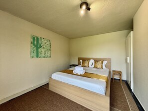 A hotel room with a bed, a small bedside table, a wall-mounted artwork, and a ceiling light fixture. - VILAMOURA BROWNS VILLA WITH POOL by HOMING (Vilamoura)