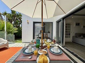 An outdoor dining area with a table set for breakfast, including plates, cups, and a variety of food items. - VILAMOURA BROWNS VILLA WITH POOL by HOMING (Vilamoura)