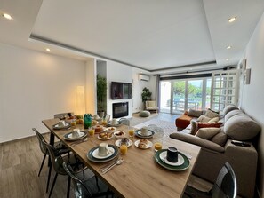 A modern living space with a dining area, a sofa, and a television. - VILAMOURA BROWNS VILLA WITH POOL by HOMING (Vilamoura)