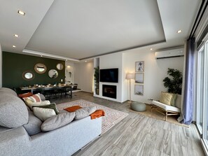 A modern living room with a sofa, dining area, and a TV mounted on the wall. - VILAMOURA BROWNS VILLA WITH POOL by HOMING (Vilamoura)