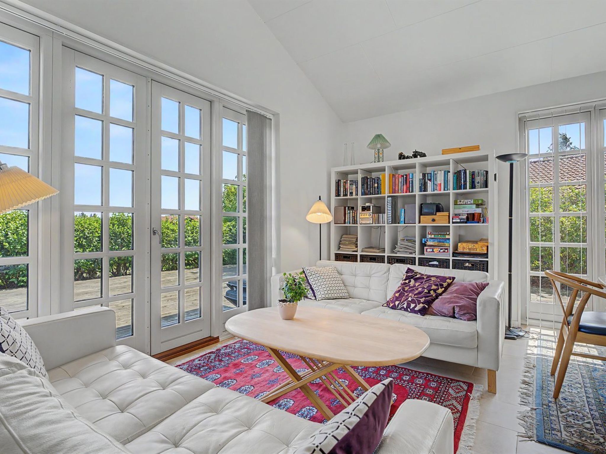 A spacious living room with a white sofa, a coffee table, and a bookshelf filled with books.