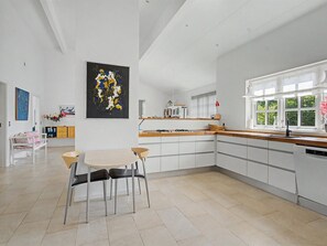 Een moderne keuken met een eethoek, witte kasten en een groot raam.