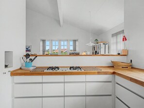 Eine moderne Küche mit weißen Schränken, einer Holz Arbeitsplatte und einem Gasherd.