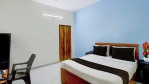 Ein Hotelzimmer mit einem Bett, einem Schreibtisch, einem Stuhl, einem Deckenventilator und einer Tür.