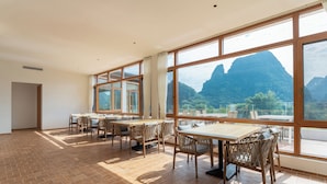 Una habitación amplia con grandes ventanales, muebles de madera y vistas a las montañas.