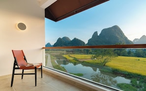 A balcony with a view of a river, rice fields, and mountains. - Yuetian Life Hotel (Guilin)