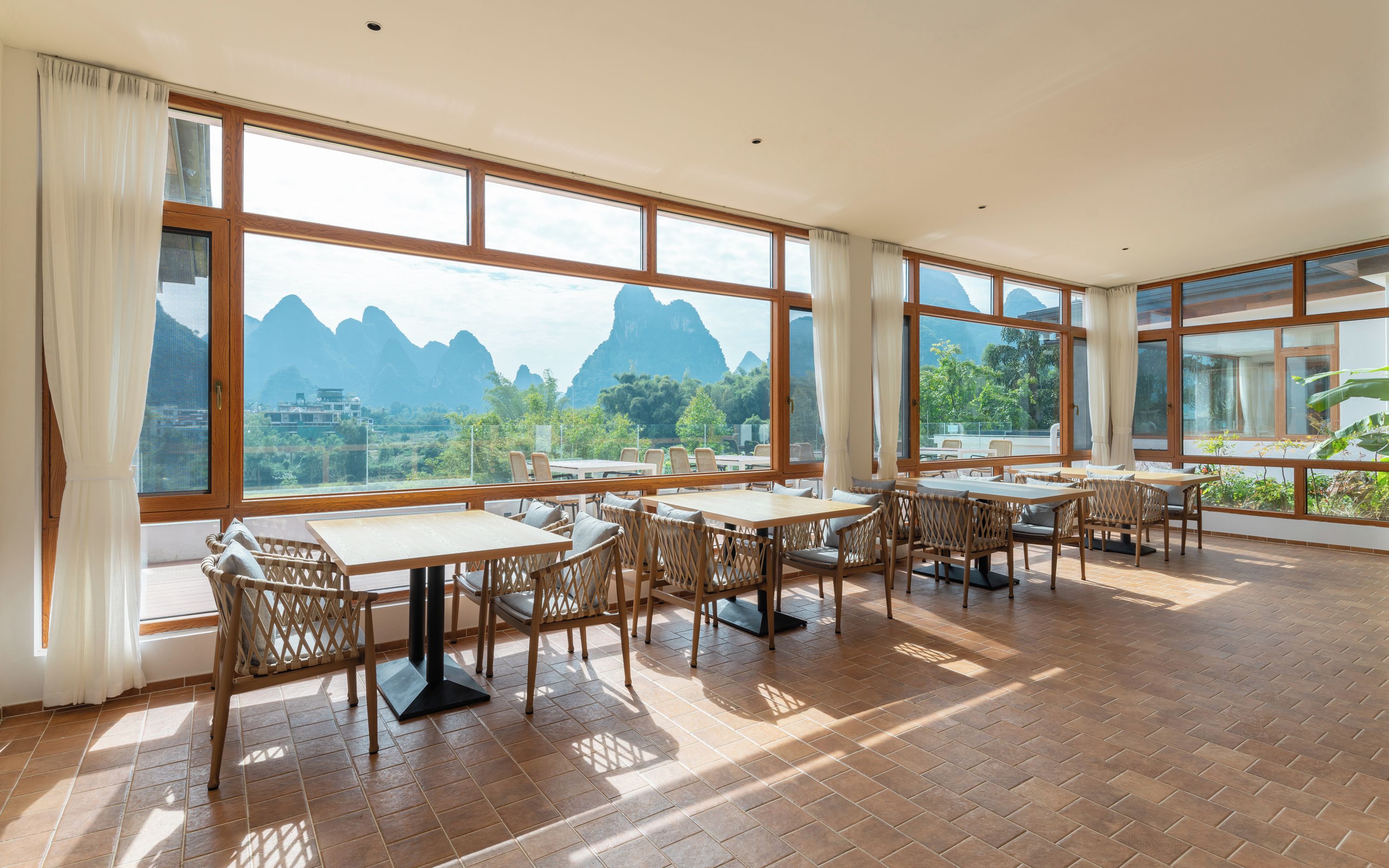 Un comedor amplio con ventanas grandes que ofrecen vista a la montaña. Mesas y sillas dispuestas para comer.
