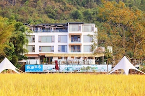 A multi-story hotel with balconies, a covered outdoor seating area, and a signboard in front. - Yuetian Life Hotel (Guilin)