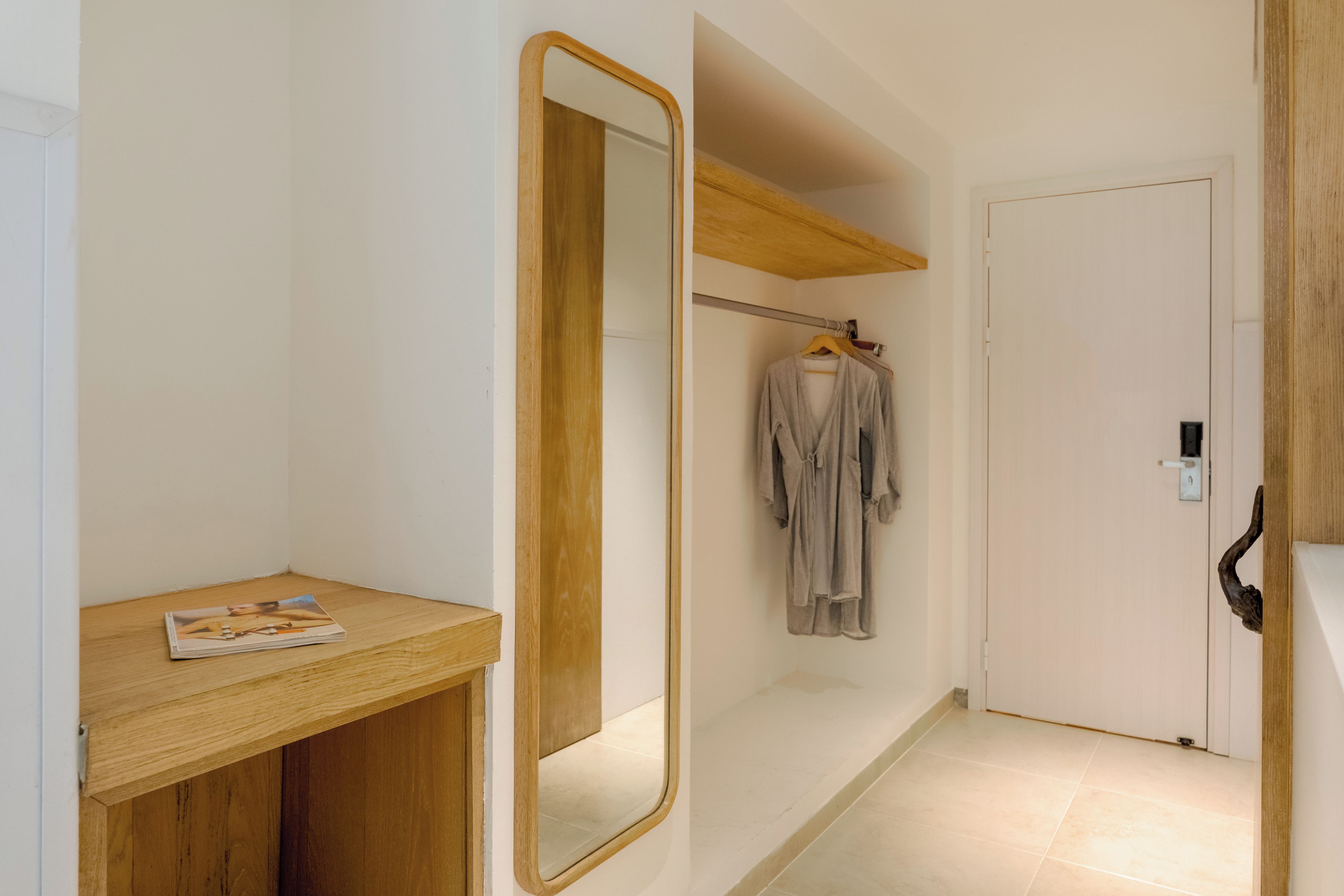 A modern bathroom with a wooden vanity, a large mirror, and a hanging robe.