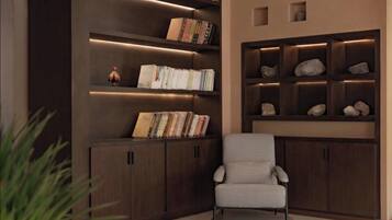 A modern library with dark wood shelving, a checkered armchair, and decorative rocks.