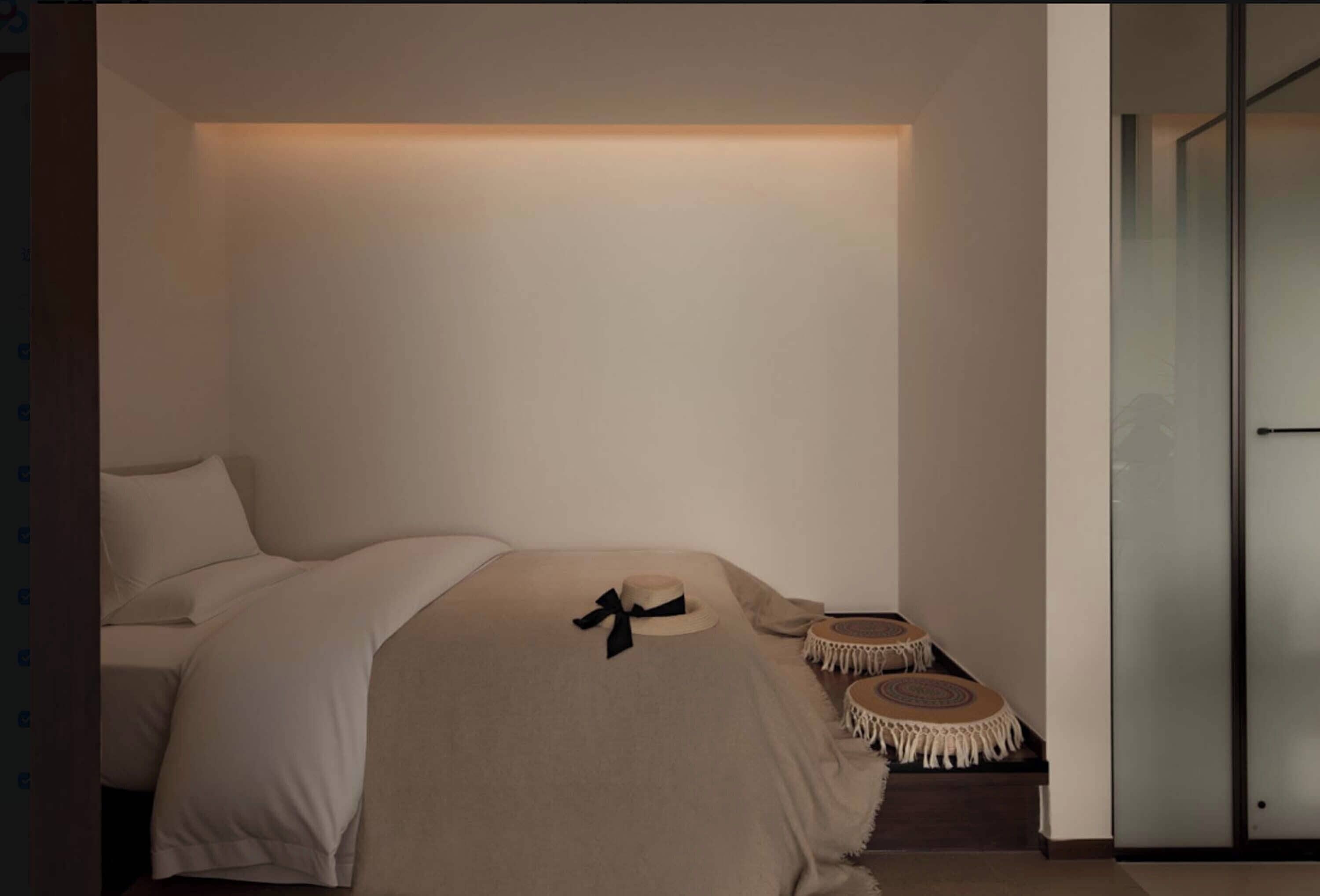 A minimalist bedroom with a bed, bedside tables, and a wall-mounted light.