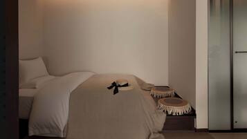 A minimalist bedroom with a bed, bedside tables, and a wall-mounted light.