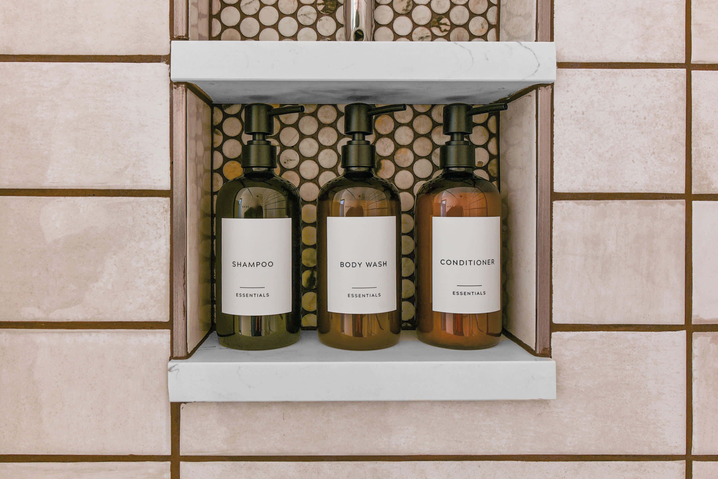 Un estante con tres botellas de champú, gel de baño y acondicionador.