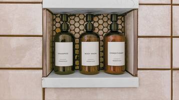 Un estante con tres botellas de champú, gel de baño y acondicionador.