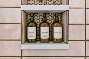 A shelf with three bottles of shampoo, body wash, and conditioner.