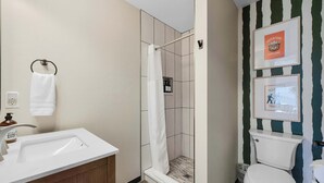 Ein Badezimmer mit Dusche, Toilette, Waschbecken und Handtuchhalter.