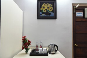 A room with a framed artwork of sunflowers, a water dispenser, a kettle, and a tray with cups and a vase of red flowers. - Super Collection O Salt Lake Formerly (Bidhannagar)