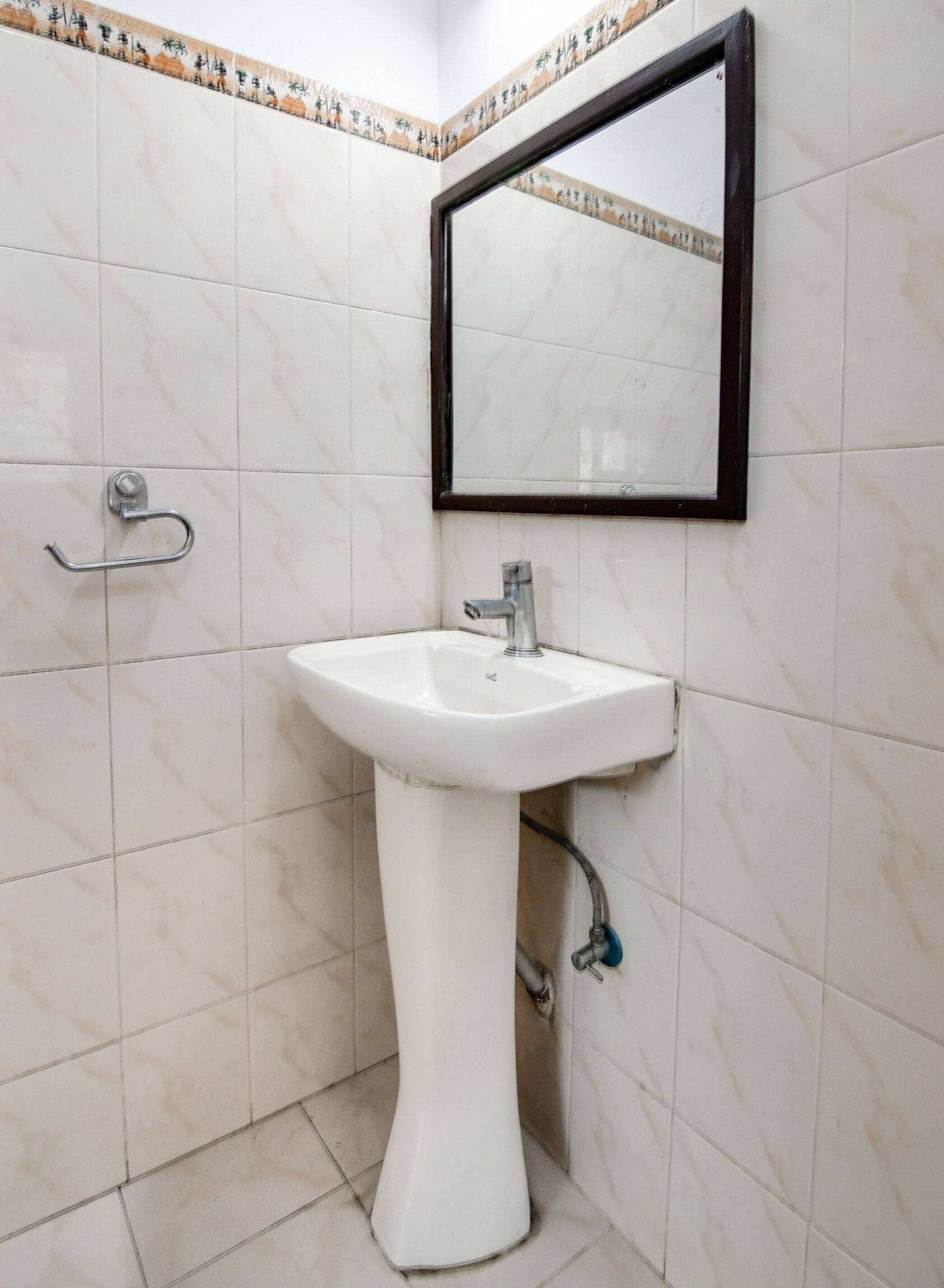 A bathroom with a white pedestal sink, a mirror, and a towel rack.