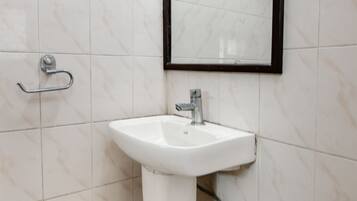 A bathroom with a white pedestal sink, a mirror, and a towel rack.