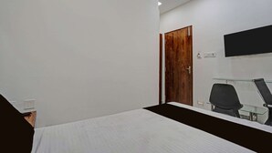 Une chambre à coucher avec un lit, une porte en bois, un téléviseur fixé au mur et une chaise.