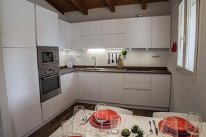 A modern kitchen with white cabinets, a built-in oven, a microwave, and a sink. - Villa 10 minutes from Piscina Rei beach (Castiadas)