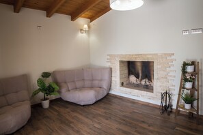 A living room with a beige sofa, a fireplace, wooden flooring, and a ceiling with exposed beams. - Villa 10 minutes from Piscina Rei beach (Castiadas)