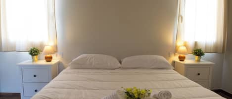 A hotel room with a large bed, two bedside tables with lamps, and a window with curtains.