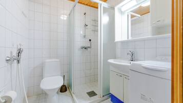 A modern bathroom with a toilet, shower, and sink.