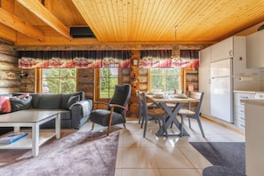 A log cabin interior with a dining area, kitchen, and living space.