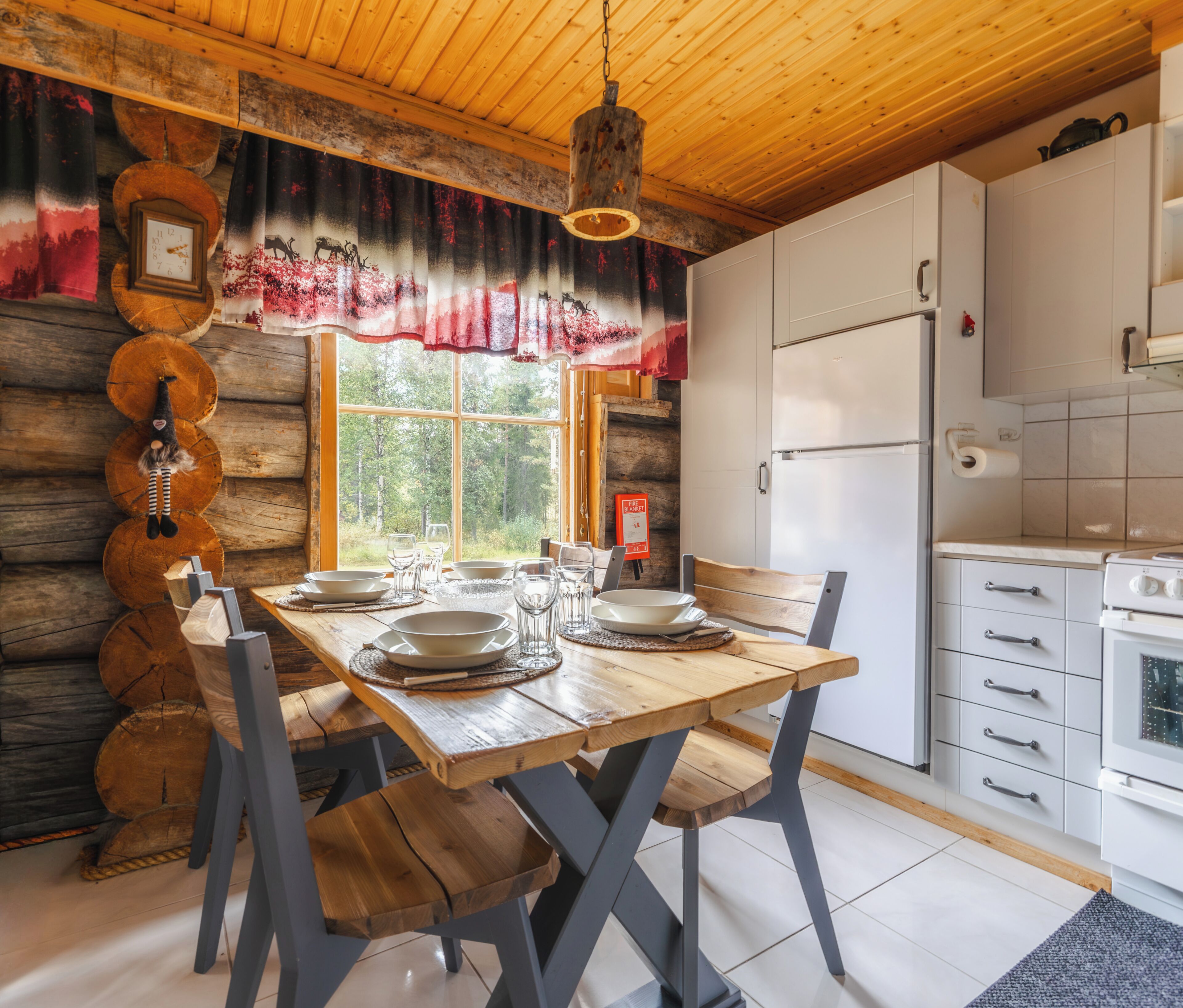 A wooden dining table set with plates and glasses, a refrigerator, and a kitchen counter.