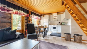 A log cabin interior with a dining area, kitchen, and a staircase.