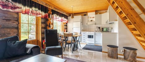 Ein Blockhaus-Interieur mit Essbereich, Küche und einer Treppe.