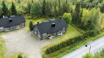 A lodge with two cabins, each featuring a black roof and log construction, surrounded by dense forest.