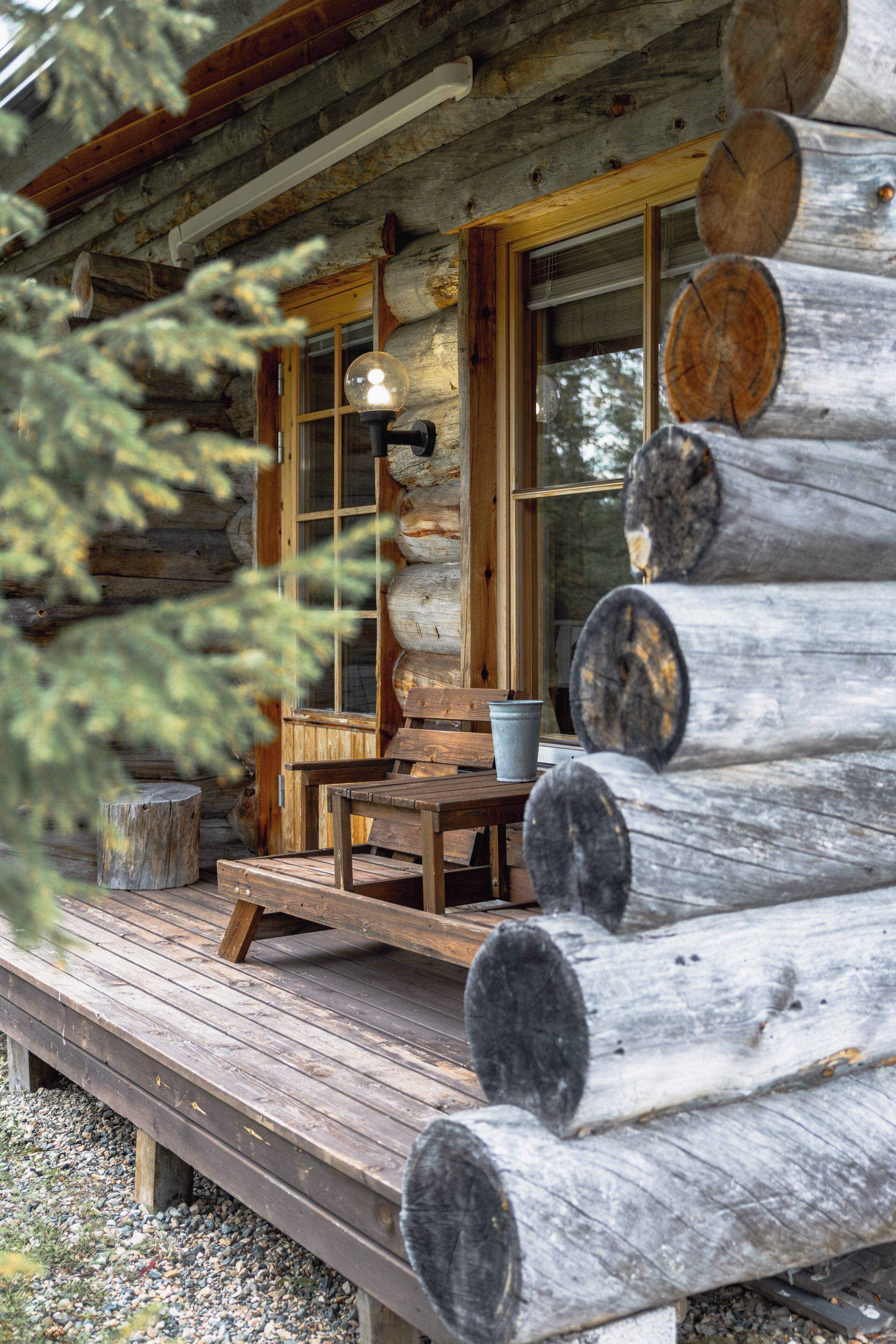 A rustic wooden cabin with a porch, a table, and a bench.