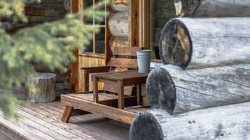 A rustic wooden cabin with a porch, a table, and a bench.