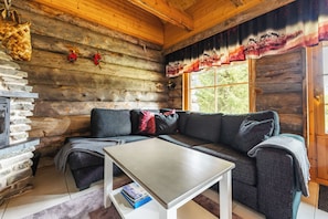 A log cabin interior with a sofa, a table, and a fireplace.