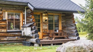 A log cabin with a porch, a table, and chairs. - Villa Mäkitupa (Kittilä)