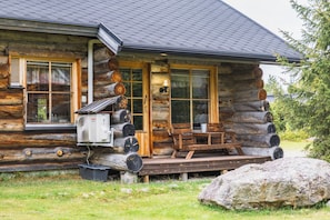 A log cabin with a porch, a table, and chairs.