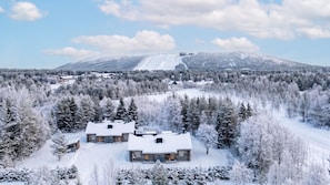 A snow-covered lodge with a ski slope in the background.