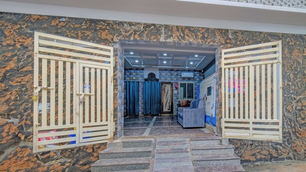 Entrada de hotel con pared de mármol, una escalera que conduce al interior y una cortina azul.