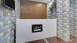 Un área de recepción con pared de diseño de piedra, panel de listones de madera y un letrero que indica 'Collection' y 'Company-Served'.