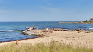 Ein Strand mit Menschen, Booten und einem Gebäude im Hintergrund.